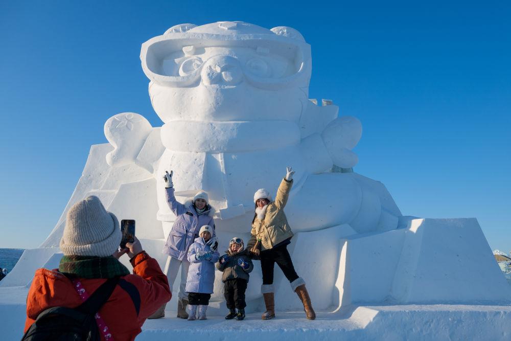 2025年1月3日，在黑龍江哈爾濱冰雪大世界園區(qū)，游客與亞冬會(huì)吉祥物雪雕“濱濱”合影