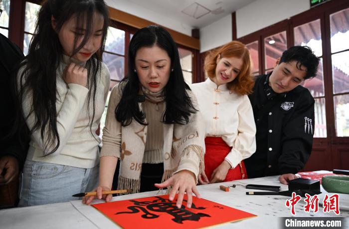 1月20日，西泠印社社員李硯（左二）為外籍留學生講述蛇年福字貼創(chuàng)作靈感。當日，來自巴西、馬來西亞、加納、哈薩克斯坦的外籍留學生在浙江杭州西泠印社體驗福貼、春聯(lián)和篆刻，感受古老的中國傳統(tǒng)文化。中新社記者 王剛 攝