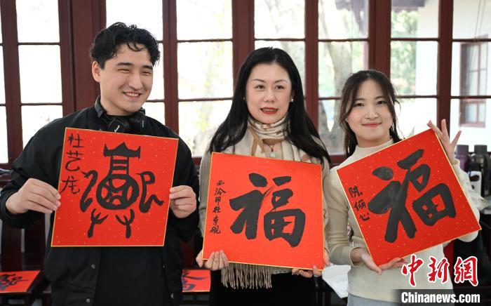 1月20日，外籍留學生和西泠印社社員李硯(中)展示各自創(chuàng)作的福貼。當日，來自巴西、馬來西亞、加納、哈薩克斯坦的外籍留學生在浙江杭州西泠印社體驗福貼、春聯(lián)和篆刻，感受古老的中國傳統(tǒng)文化。中新社記者 王剛 攝
