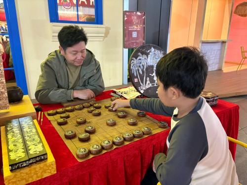柯秋楓與市民下椰雕象棋。人民網(wǎng) 陳葉欣攝
