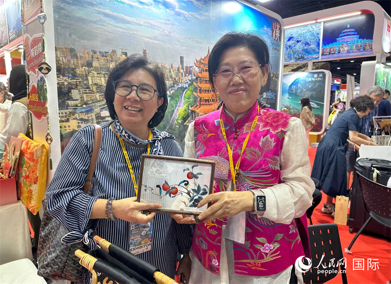 中國“大冶刺繡”傳承人劉小紅（右）參加泰國國際旅游展，向觀眾介紹中國非遺刺繡針法。人民網(wǎng)記者 簡承淵攝