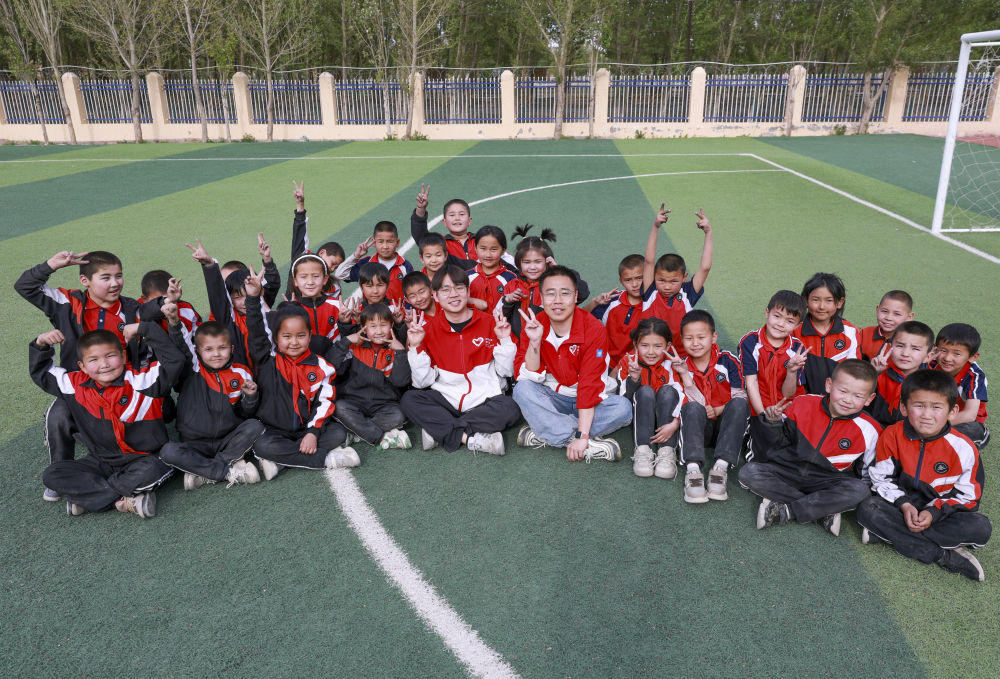 4月23日，在新疆克州阿圖什市哈拉峻鄉(xiāng)謝依特小學(xué)，支教教師王俊文（中左）、李軻凡（中右）和學(xué)生在一起。